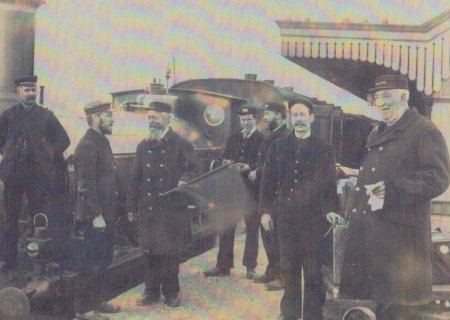 B&W photograph of Charles Ambridge (stationmaster, on the right) and his staff pictured in the 1890s on the platform at Radley Station with a steam train behind them